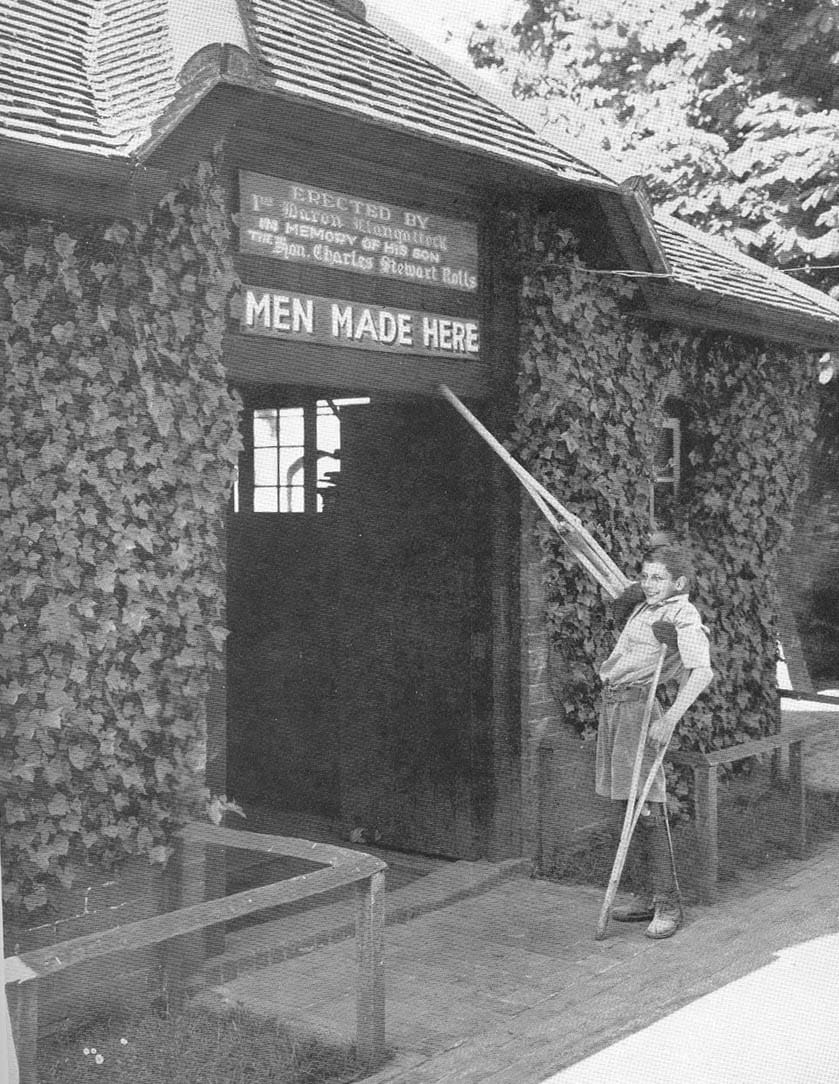 carpentry school boy with crutches in front of a sign reading men made here