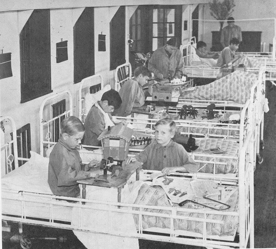 crafts in bed kids in lined up beds with wooden pieces on boards on their laps