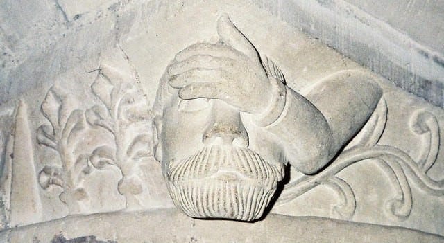 Sculpture of a man pressing a hand to his forehead representing a migraine headache.