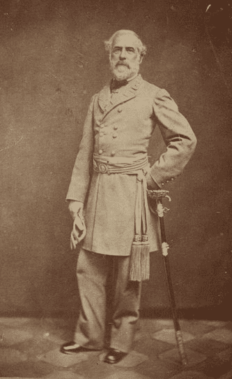 A bearded man with short light-colored hair leaning on a sword and wearing a dress coat and a belt with two long tassels