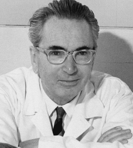 Photo of Viktor Frankl, smiling with crossed arms in lab coat and glasses