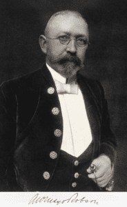 Arthur William Mayo-Robson: A man with a full mustache and beard in a formal period suit and vest, with signature at bottom.