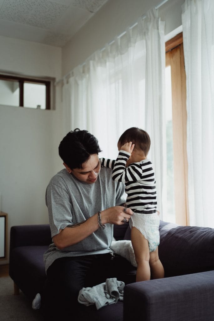 A young man adjusting a child's diaper